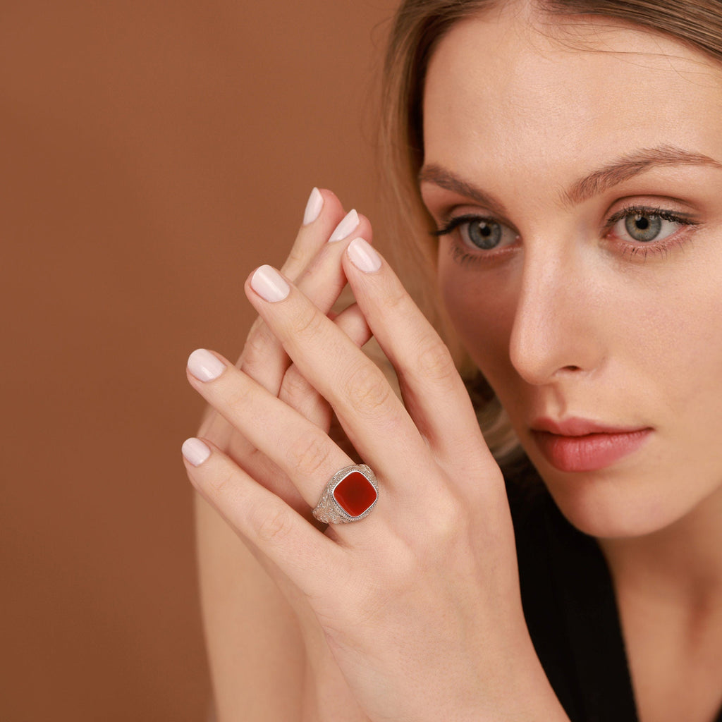 Woman wearing a red agate ring on a brown background