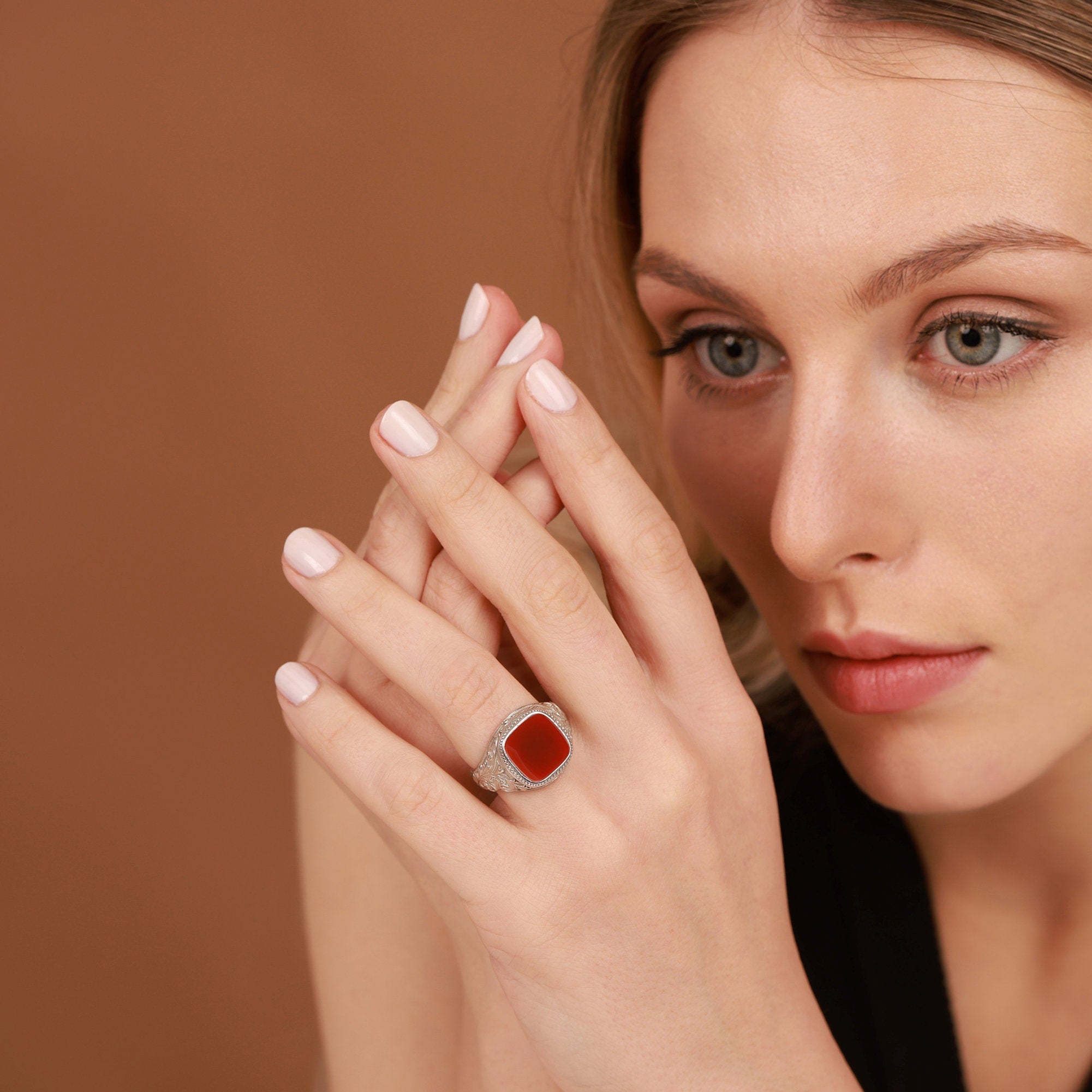 Woman wearing a red agate ring on a brown background