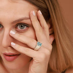 Woman wearing a ring with a blue gemstone on a brown background