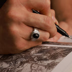 Hand holding a pen with a cabochon black onyx ring