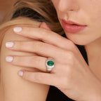 A woman wearing a ring with a green stone on her hand