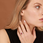 A woman wearing a red gemstone skull ring on a brown background