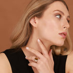 Woman wearing a tiger's eye ring on her finger against a brown background