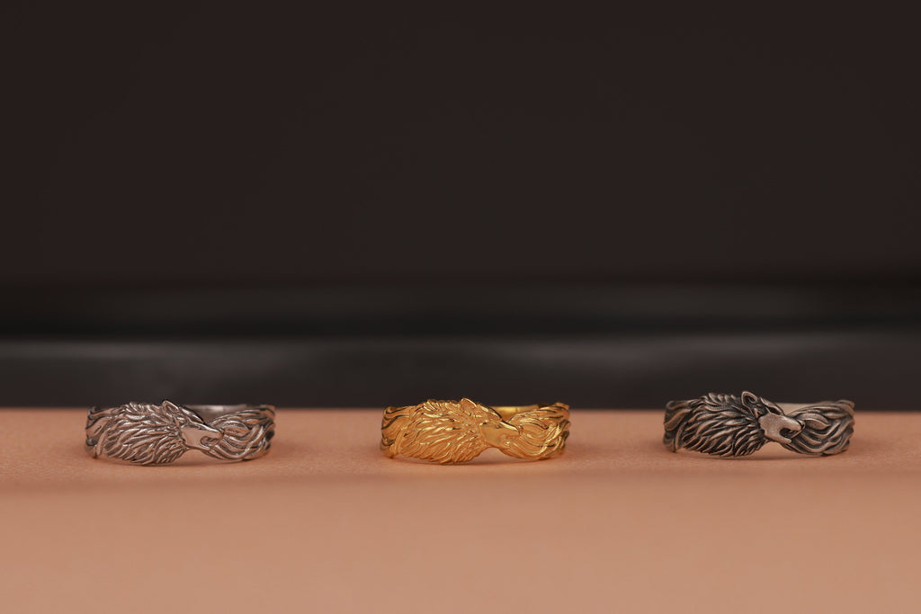 Three rings, two silver and one gold, on a brown surface with a dark background