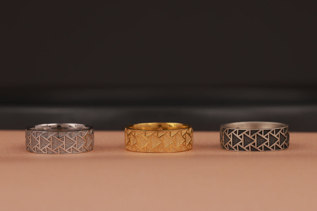 Three rings with geometric patterns on a brown surface and a dark background