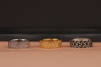 Three rings with geometric patterns on a brown surface and a dark background