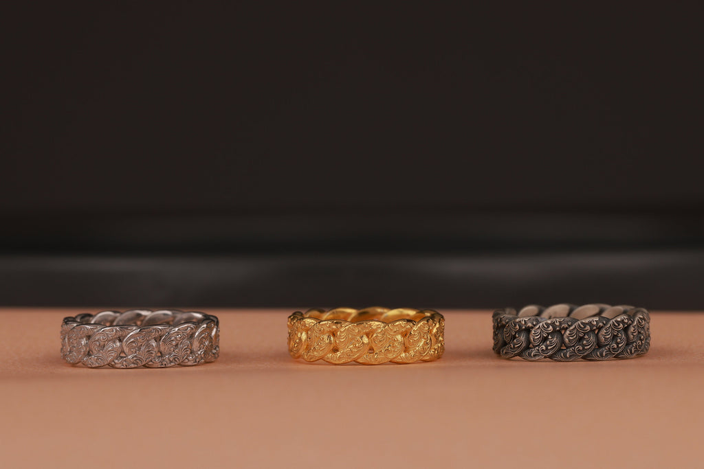 Three rings, two silver and one gold, on a brown surface with a dark background