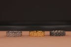 Three rings, two silver and one gold, on a brown surface with a dark background