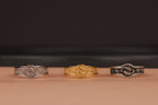 Three rings of different designs on a brown surface with a dark background