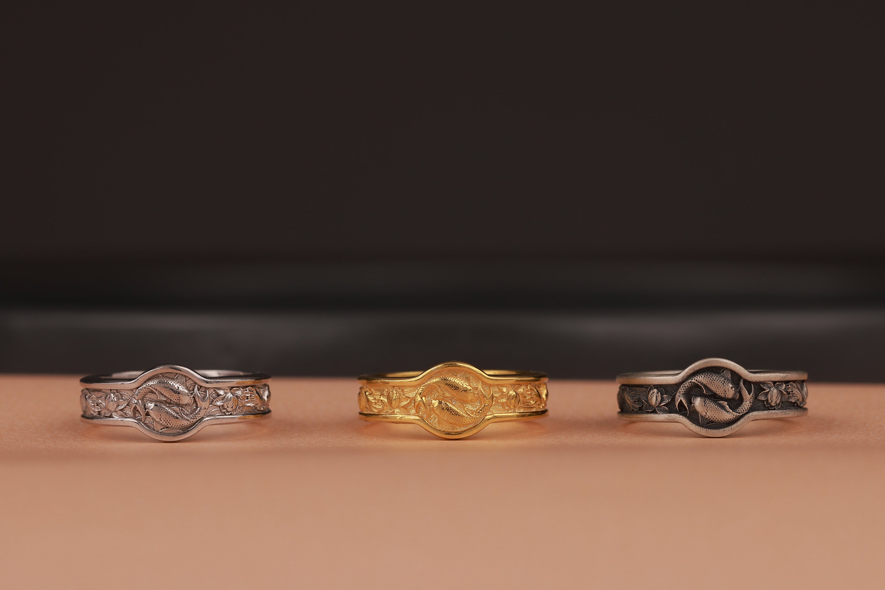 Three rings of different designs on a brown surface with a dark background