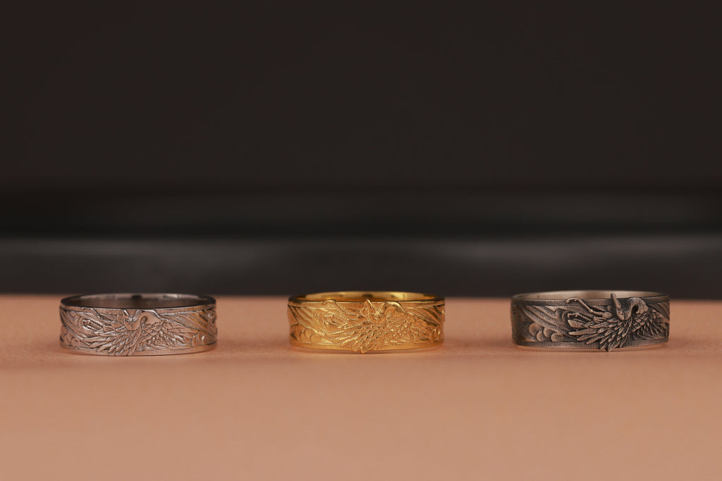 Three rings in silver, gold, and another silver color on a brown surface with a dark background.