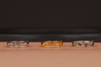 Three rings in silver, gold, and clear on a brown surface with a black background