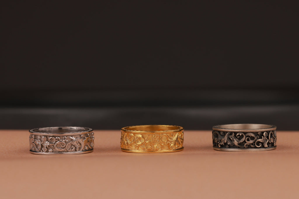 Three rings, two silver and one gold, on a brown surface with a dark background