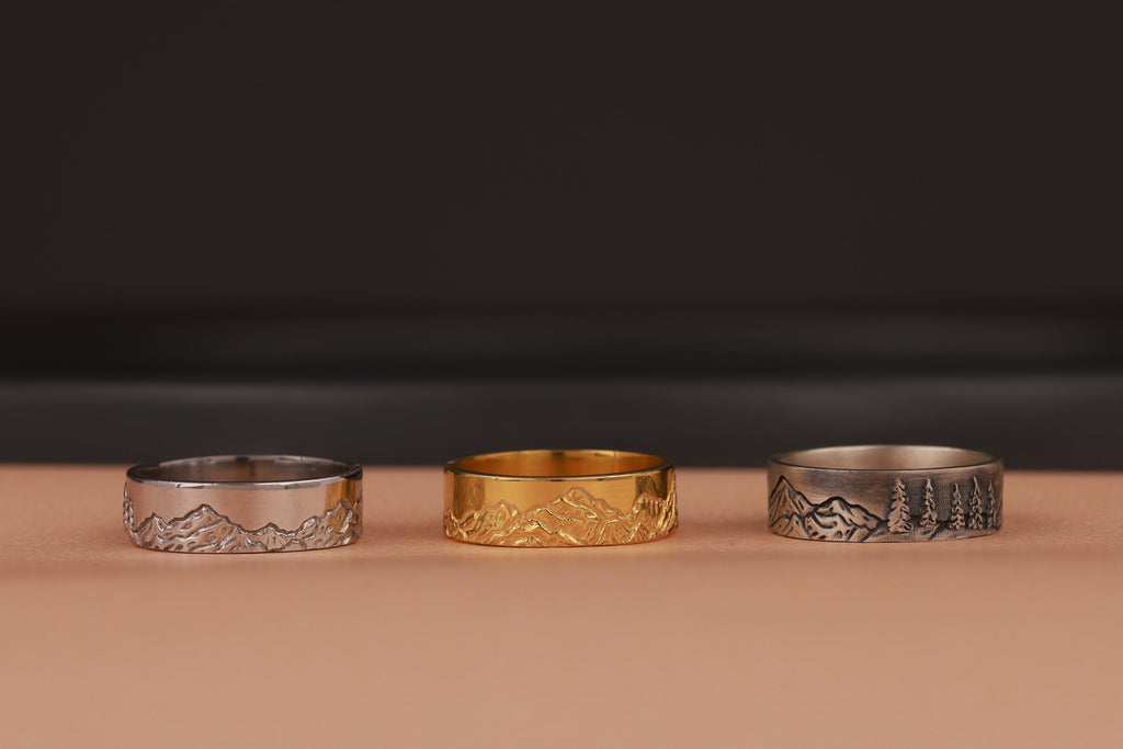 Three nature rings, two silver and one gold, on a brown surface with a dark background