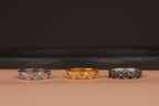 Three rings in silver, gold, and black on a brown surface with a dark background