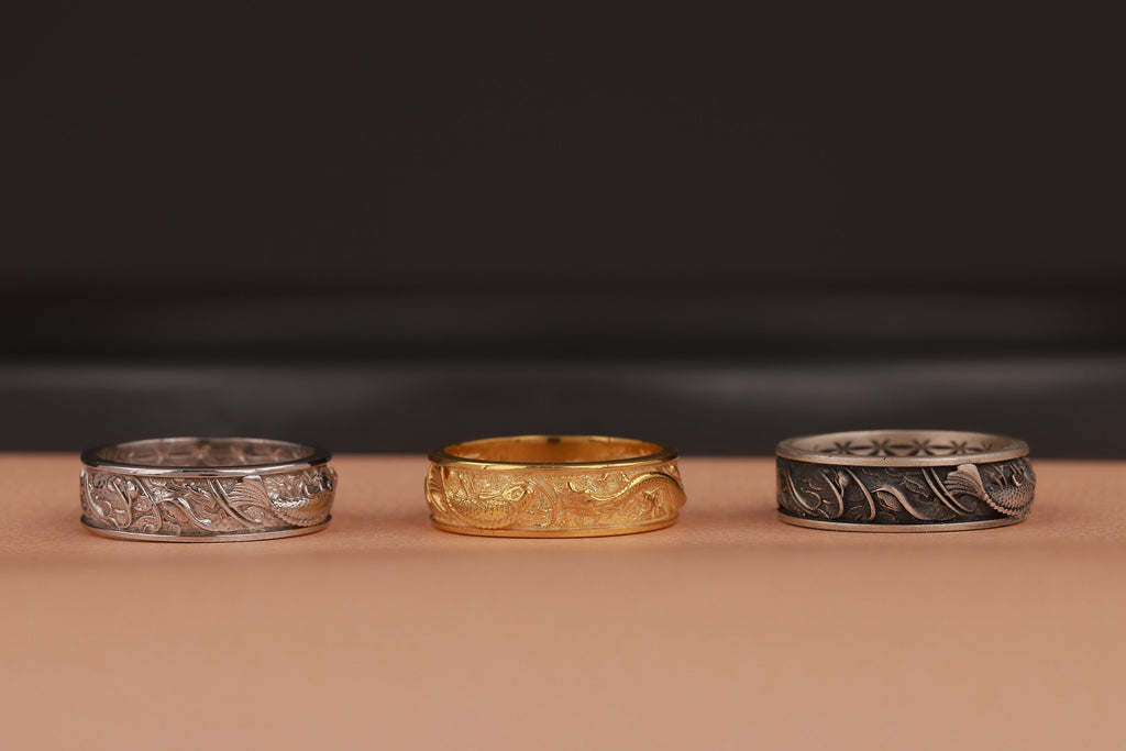 Three rings, two silver and one gold, on a brown surface with a dark background