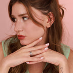 A woman wearing a chain ring with a pink background