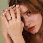 Woman with hand on face wearing a ring, against a neutral background