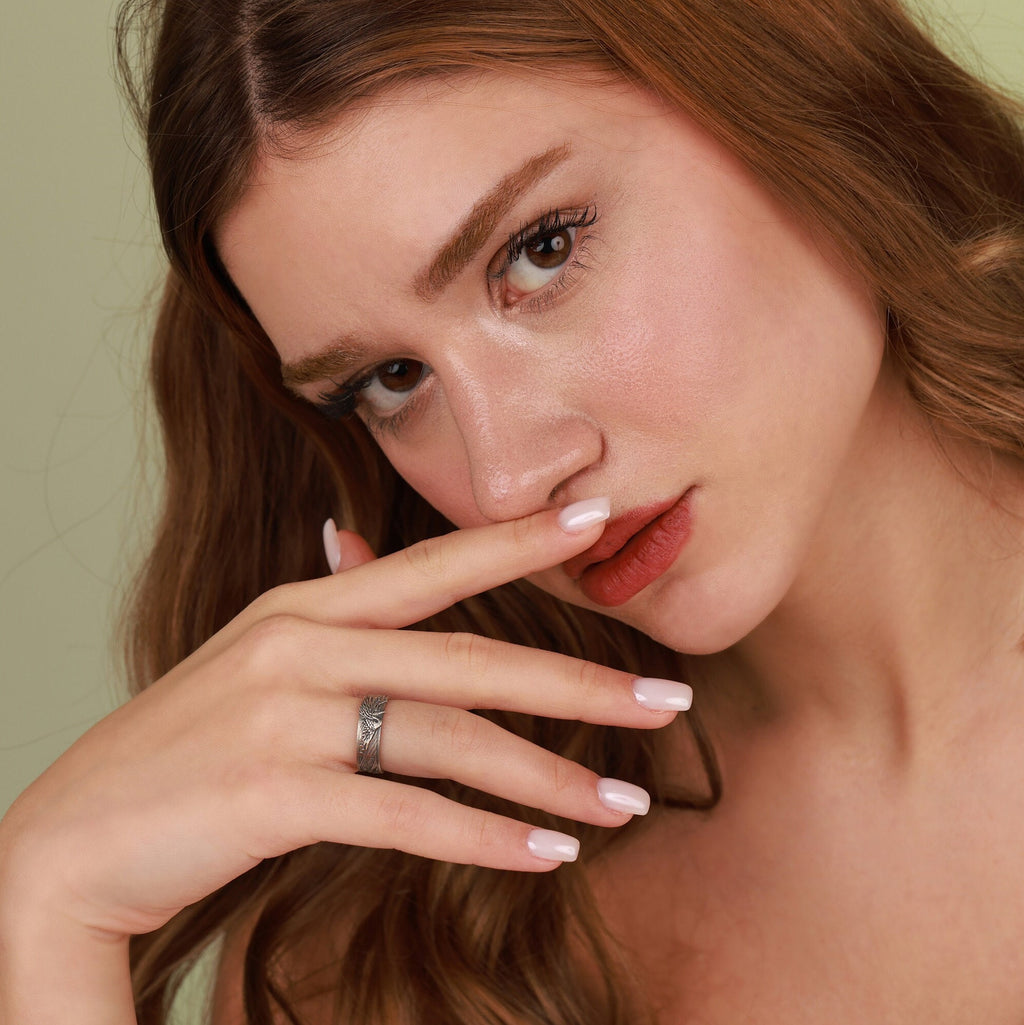 Woman with hand near her face against a neutral background