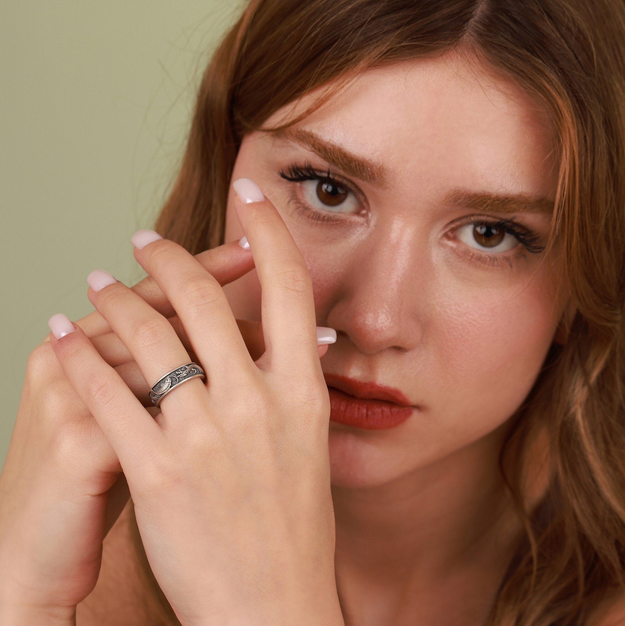 Woman with a ring on her finger against a green background