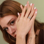 A woman wearing a ring with Egyptian symbols, holding her hands together.