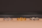 Three chain rings in silver, gold, and another silver design on a beige surface with a dark background.