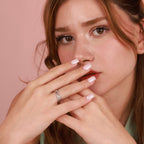 Woman wearing a polished silver feather wrap ring with a pink background
