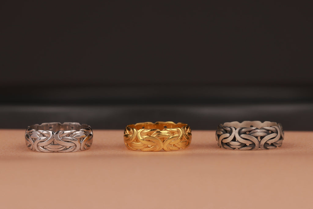 Three rings, two silver and one gold, on a brown surface with a dark background