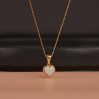 Gold necklace with a heart-shaped opal pendant on a dark background
