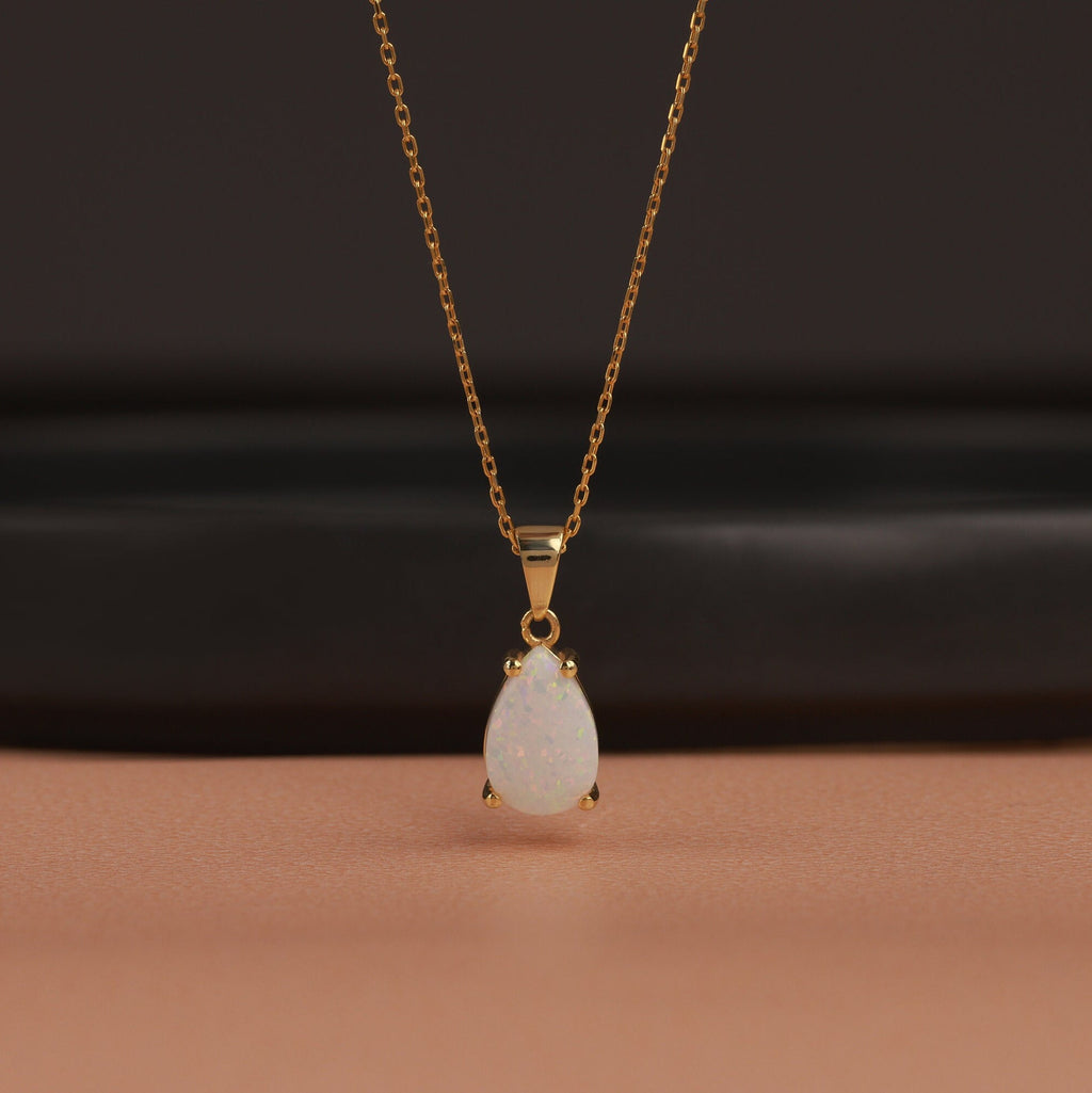 Gold necklace with a teardrop-shaped pendant on a dark background