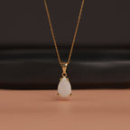 Gold necklace with a teardrop-shaped pendant on a dark background