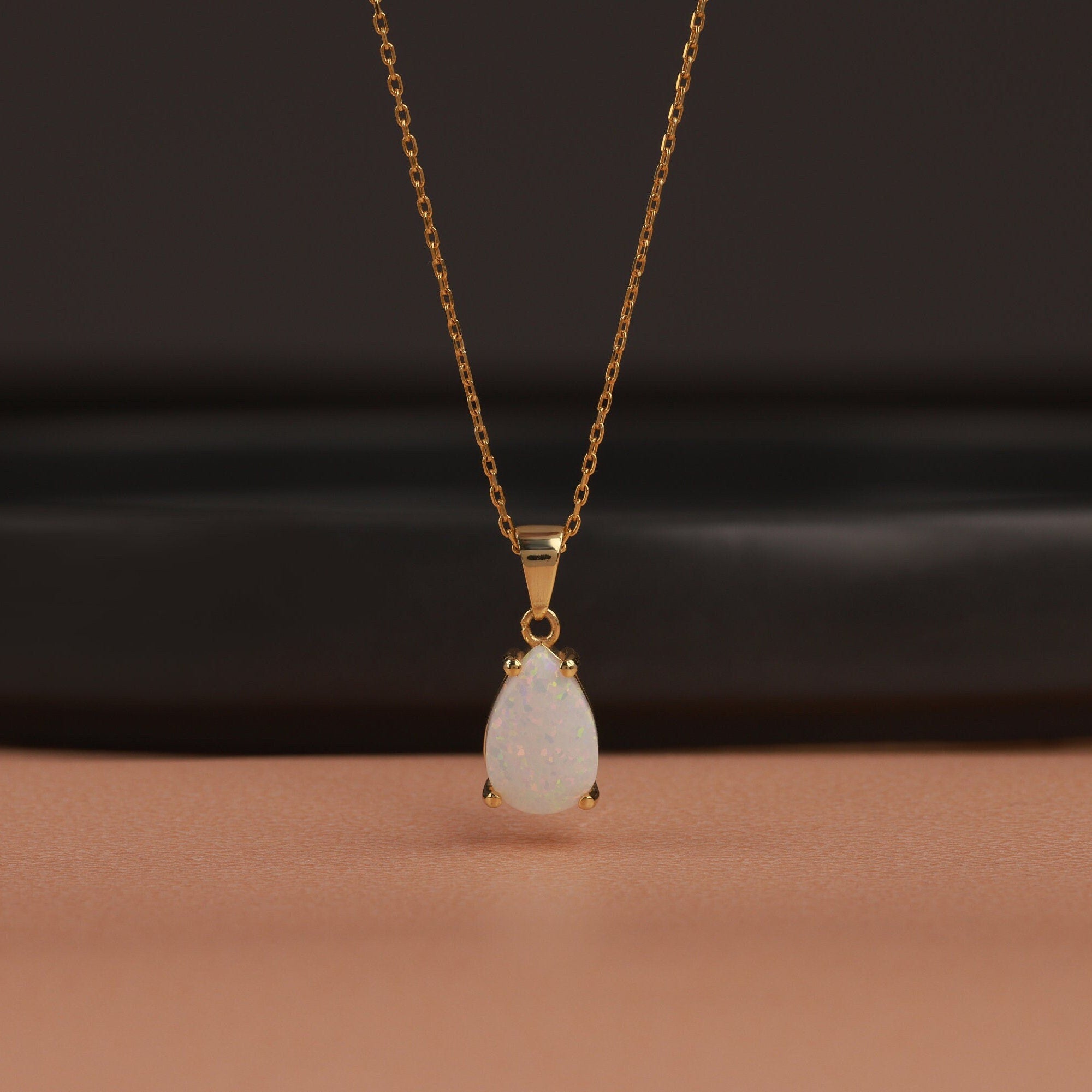 Gold necklace with a teardrop-shaped pendant on a dark background
