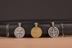 Three St Benedict cross pendants on a black and brown gradient background
