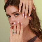 A woman with her hands wearing an oxidized ring against a green background