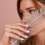 Woman holding a silver leaf against her face with a pink background