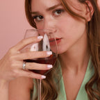 A woman holding a glass of red wine and a polished silver band ring