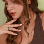 Close-up of a woman with red hair and a ring on her finger against a green background