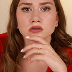 Woman wearing a gold viking ring with a plain background