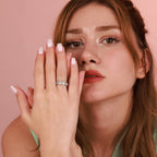 Woman with a ring on her finger against a pink background