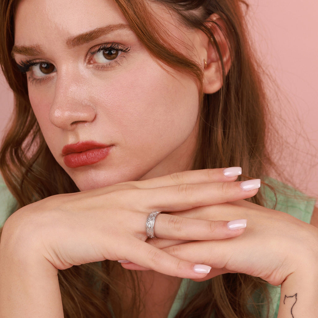 Close-up of a woman wearing a ring with a pink background
