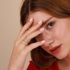 Woman wearing a gold ring with a beige background