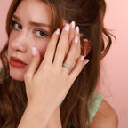 Woman wearing a diamond ring with a pink background