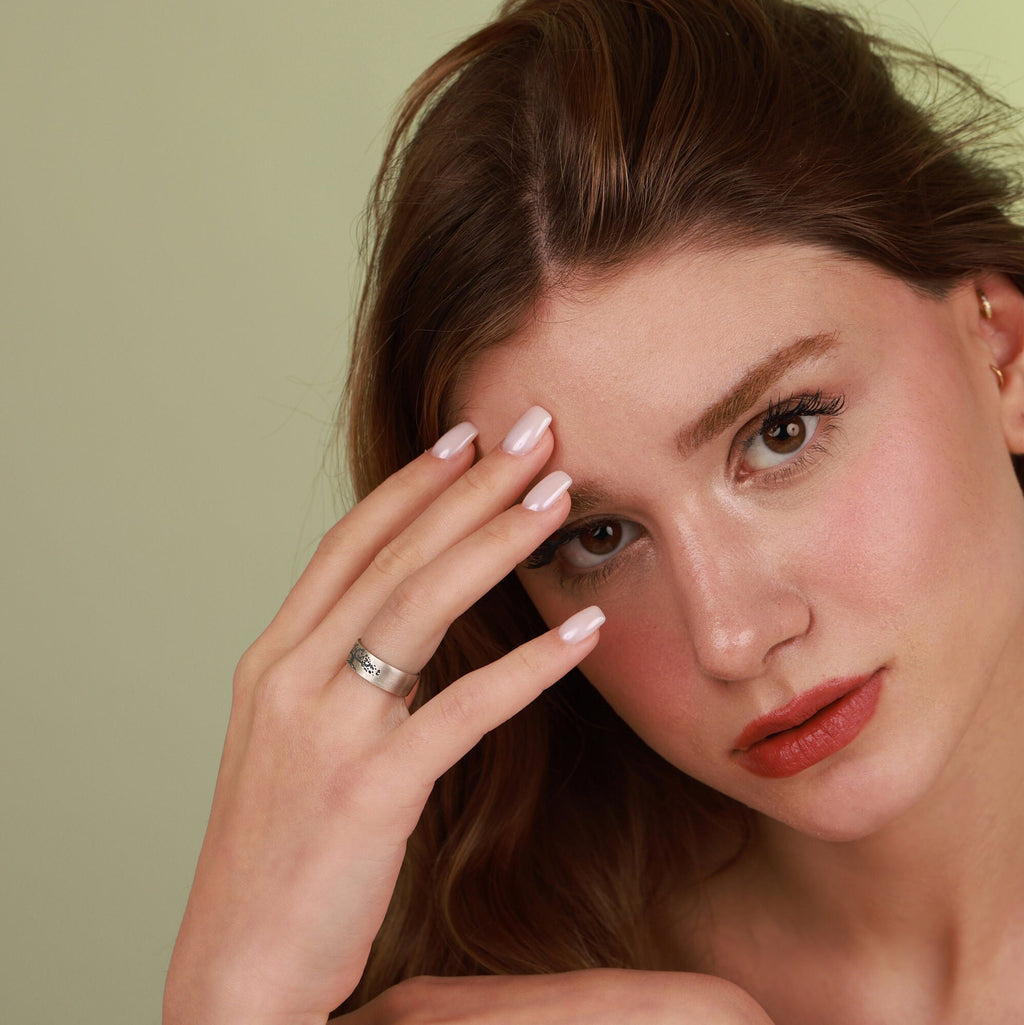 Woman with oxidized vintage wedding band ring on face against a green background