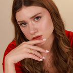Woman with long brown hair wearing a red top against a beige background