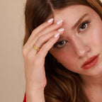 A woman wearing a gold cross band  ring 