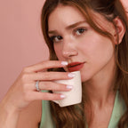 Woman wearing a polished flower ring with a pink background