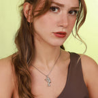Woman wearing a necklace with a polished pendant against a light green background