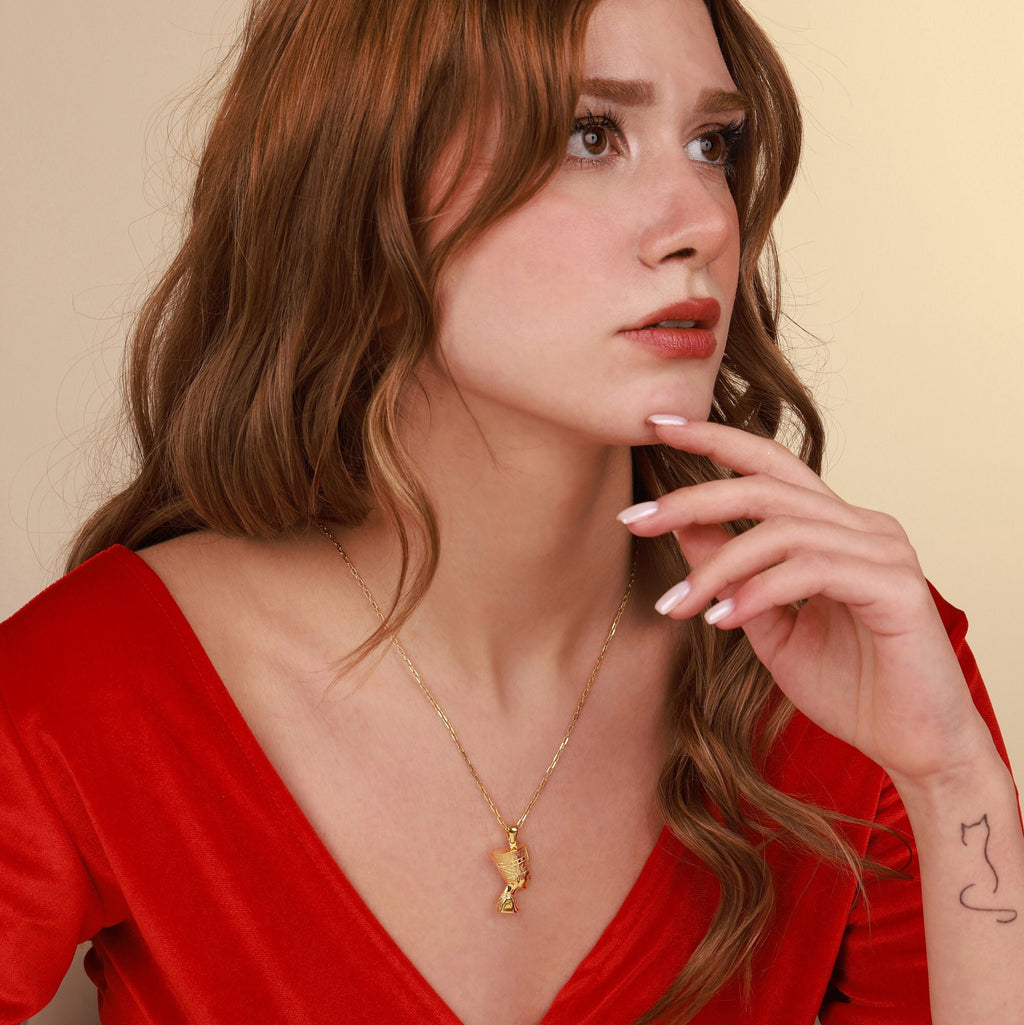 Woman wearing a gold necklace with a pendant against a beige background