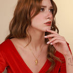 Woman wearing a gold necklace with a pendant against a beige background