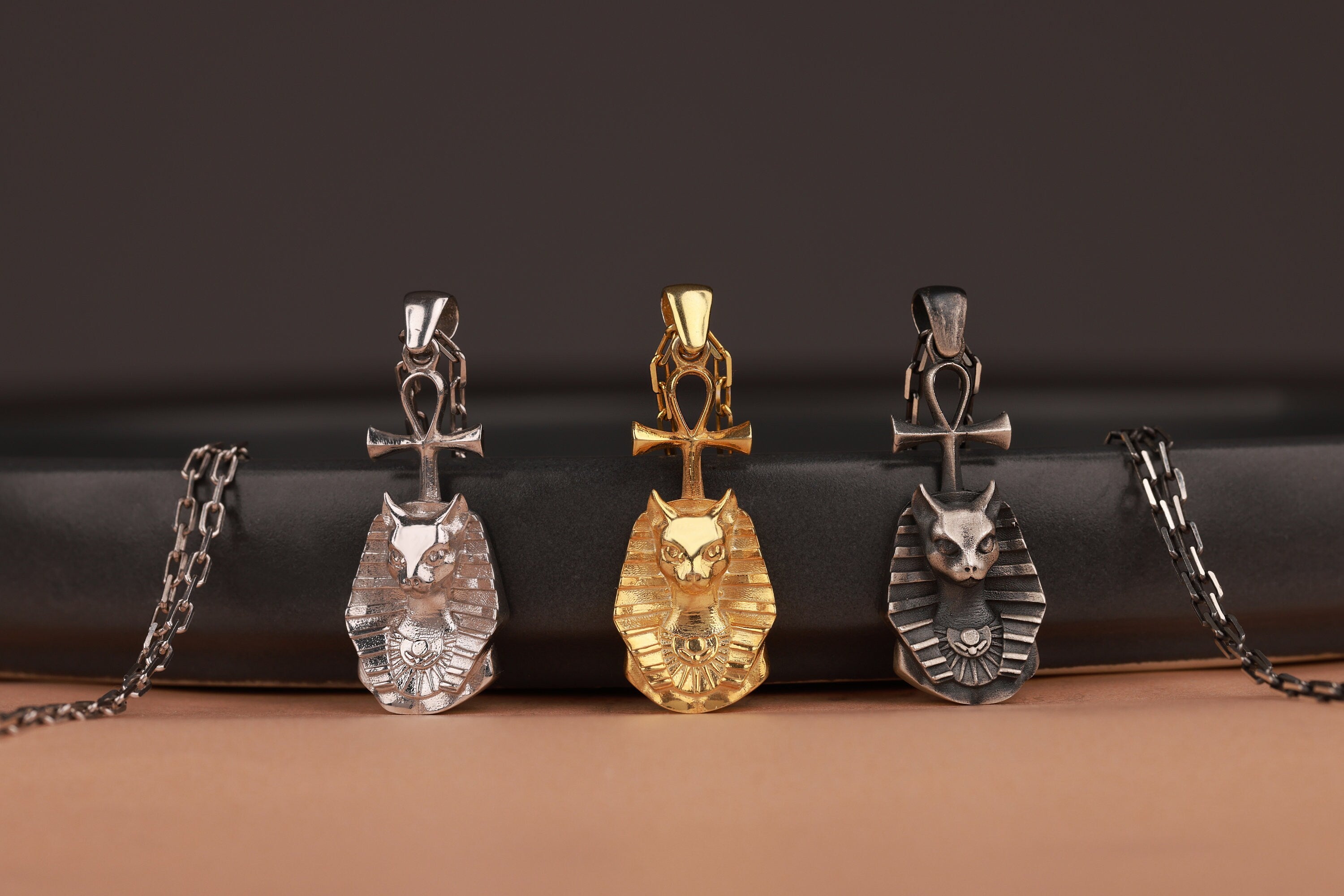 Four cat-shaped pendants on chains against a dark background